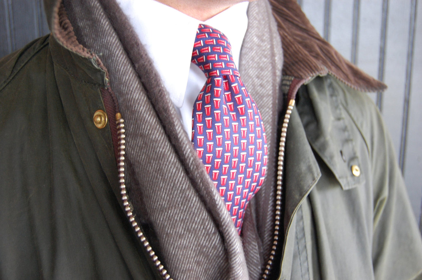Red and blue patterned necktie worn with gray cardigan and olive jacket