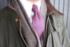 Red and blue patterned necktie worn with gray cardigan and olive jacket