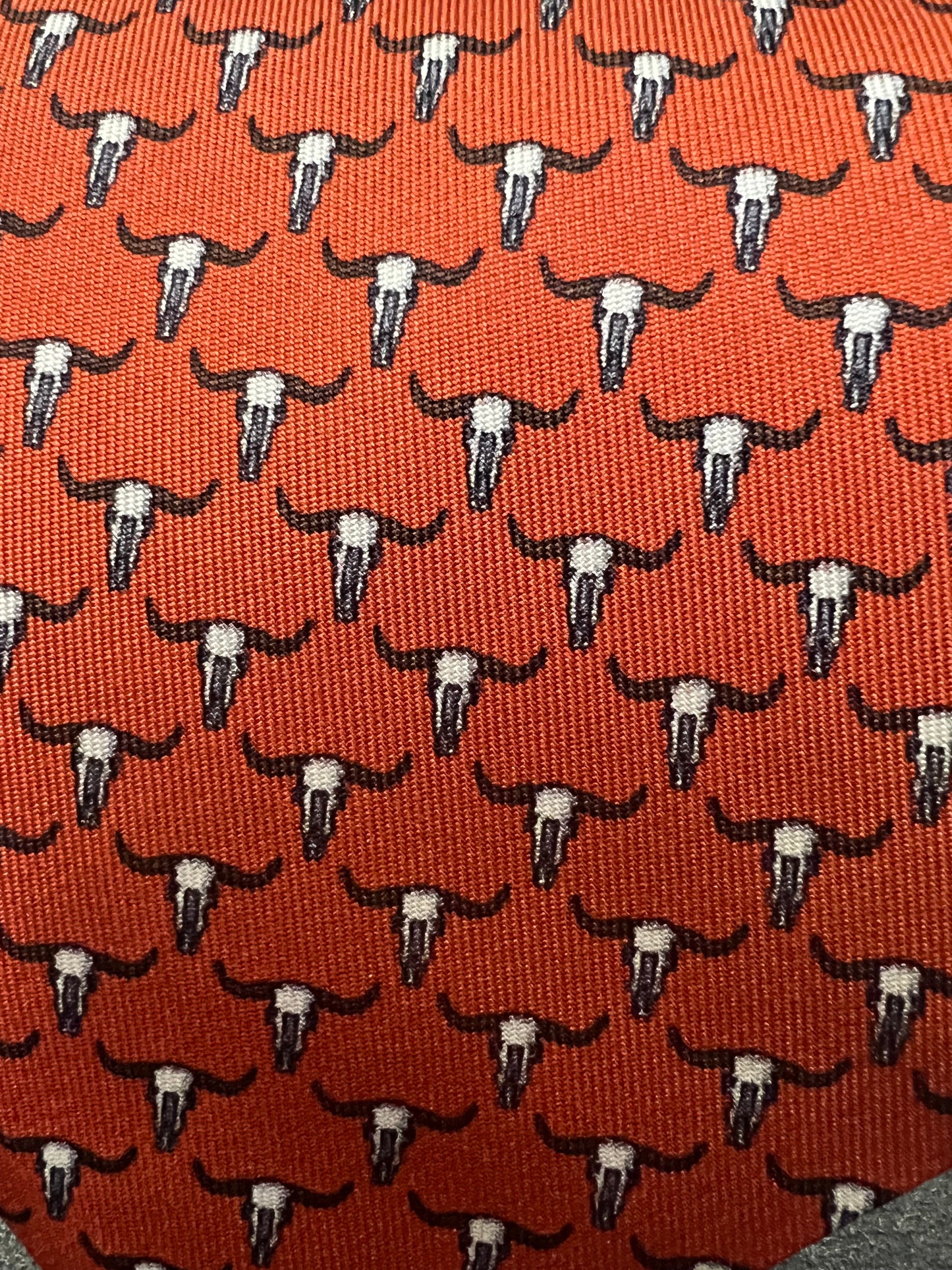 Red necktie with repeating pattern of white bull skulls with black horns