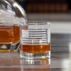Clear whiskey glass with etched Betsy Ross flag design containing amber liquid on reflective surface