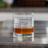 Clear whiskey glass with Betsy Ross flag design containing amber liquid on marble surface