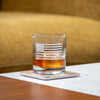 Clear whiskey glass with etched Betsy Ross flag design containing amber whiskey on napkin