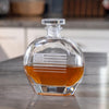 Clear glass whiskey decanter with etched American flag and 250 logo containing amber liquid