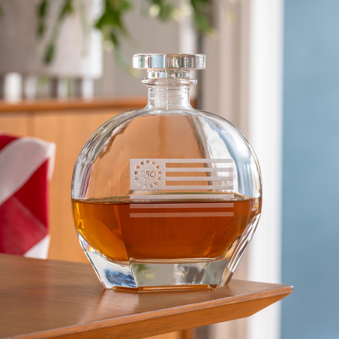 Clear glass whiskey decanter with etched Betsy Ross flag design containing amber whiskey