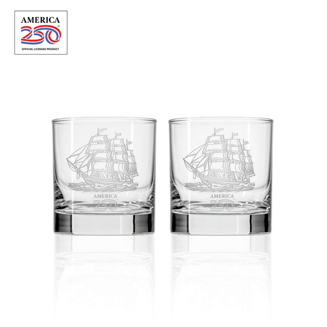 Two clear glass whiskey tumblers with etched tall ship design and America 250 logo