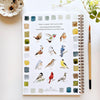Emily Lex Studio watercolor workbook showing twelve backyard birds with color swatches and painting brush