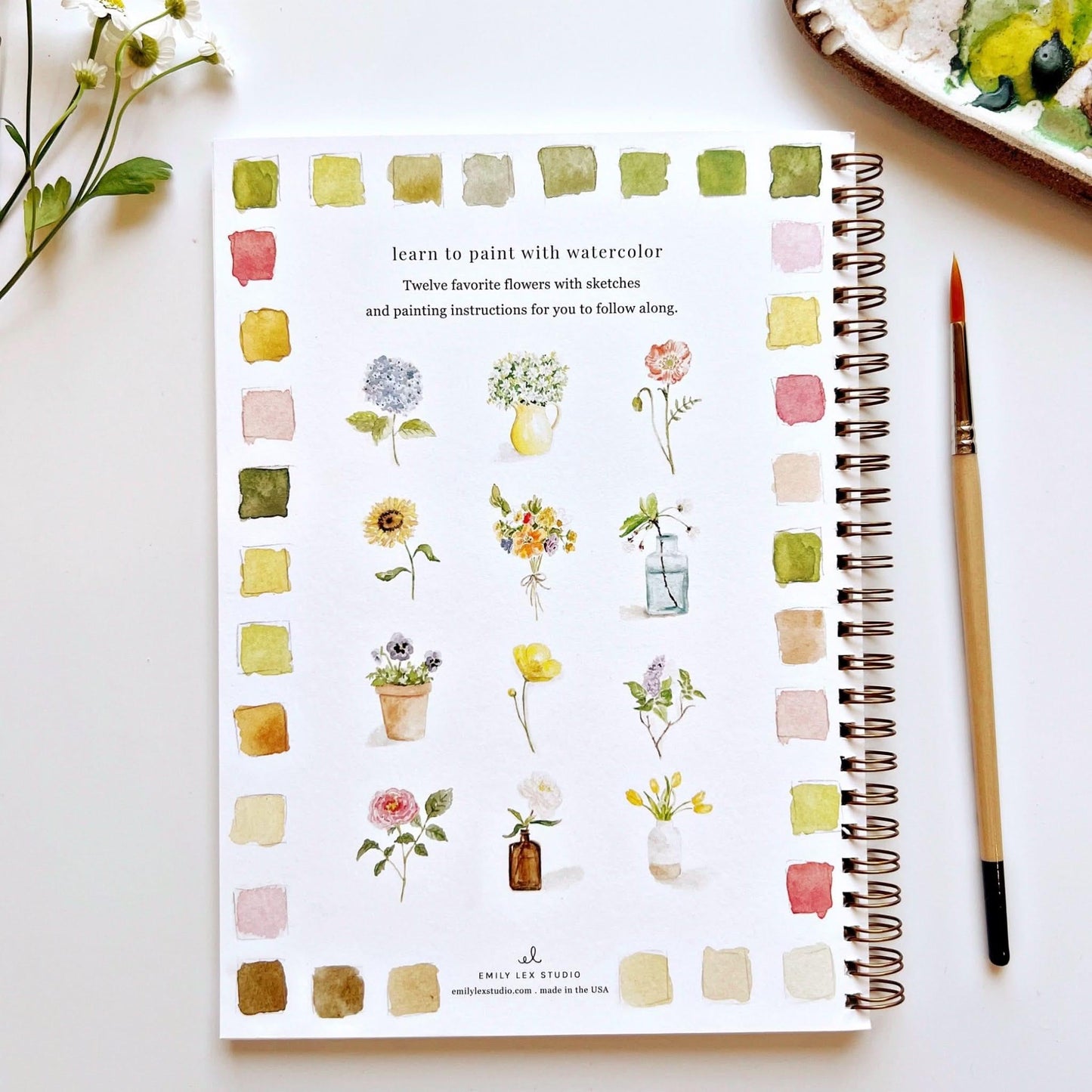 Emily Lex Studio watercolor workbook showing twelve flower tutorials with color swatches and paintbrush